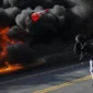 Seorang demonstran melempar kerucut lalu lintas saat api menyala selama protes terhadap razia imigrasi federal di pusat kota Los Angeles, California, AS, Minggu (8/6/2025). Foto: Daniel Cole/REUTERS 